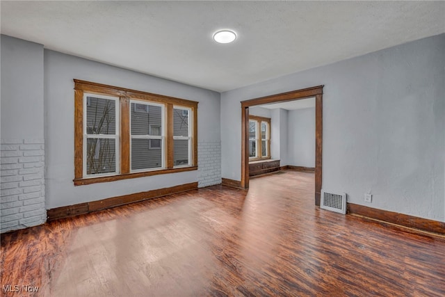 spare room with wood finished floors, visible vents, and baseboards