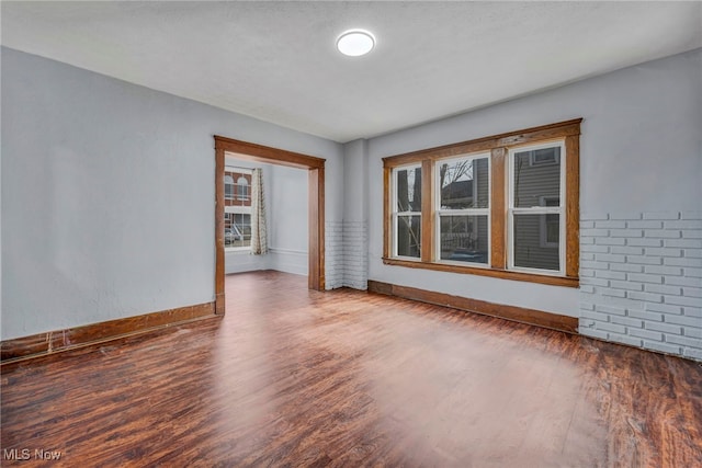 empty room with plenty of natural light, baseboards, and wood finished floors