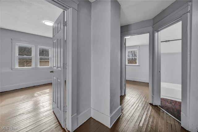 corridor featuring wood-type flooring and baseboards