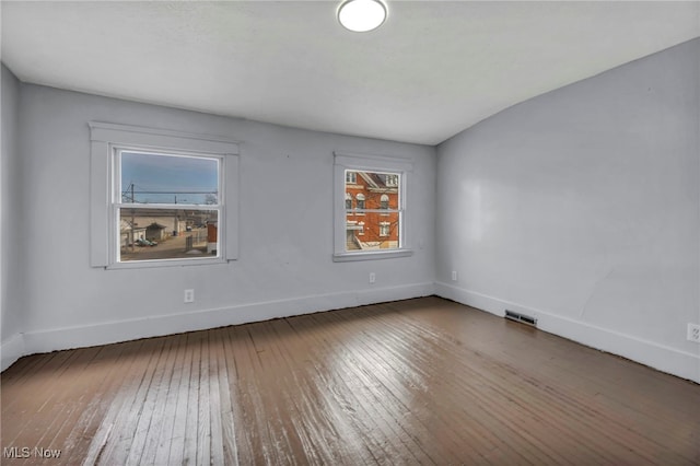 empty room with visible vents, baseboards, and hardwood / wood-style flooring