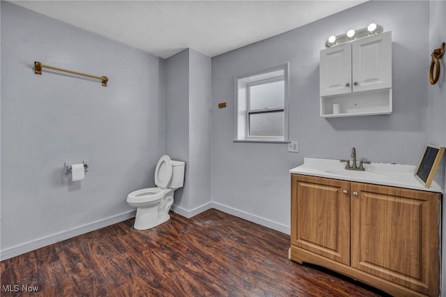 half bath with vanity, wood finished floors, toilet, and baseboards