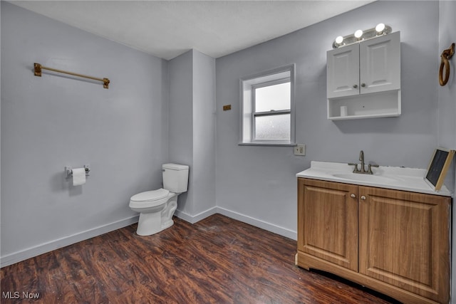 bathroom featuring toilet, baseboards, wood finished floors, and vanity