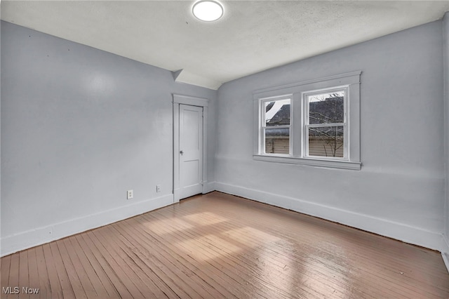 spare room with light wood-type flooring and baseboards