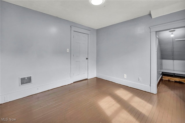 empty room with visible vents, baseboards, and hardwood / wood-style flooring