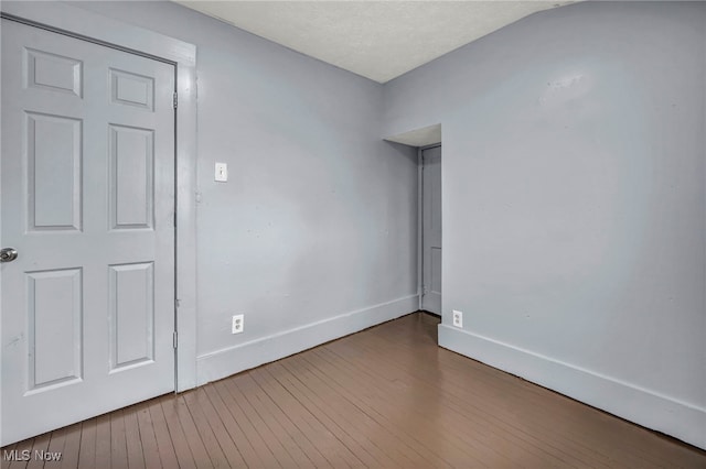 unfurnished room with baseboards and hardwood / wood-style flooring