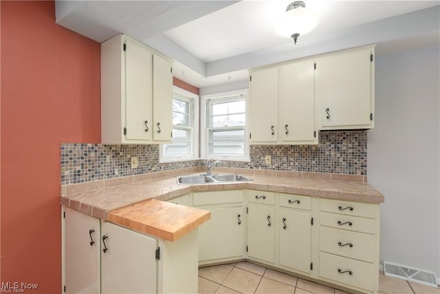 kitchen featuring tasteful backsplash, visible vents, a sink, and light tile patterned floors