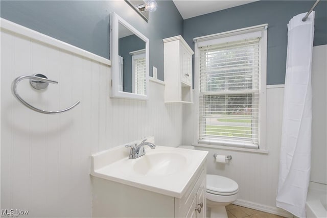 full bath with toilet, tile patterned floors, a wainscoted wall, and vanity