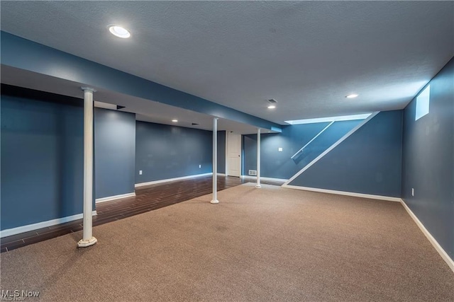 finished below grade area with a textured ceiling, carpet floors, recessed lighting, and baseboards