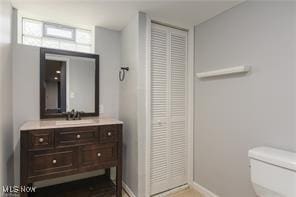 bathroom featuring toilet, baseboards, and vanity