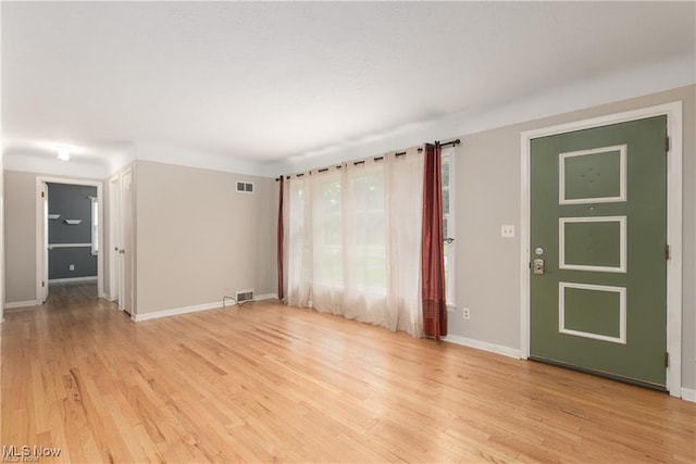 unfurnished room featuring baseboards, visible vents, and light wood finished floors