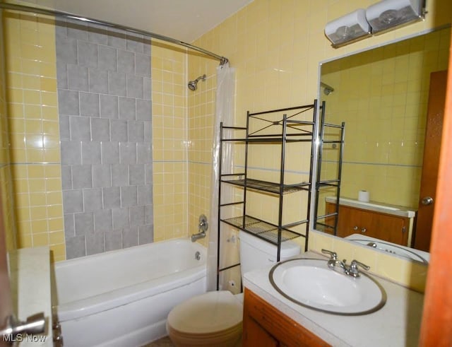 bathroom featuring shower / bathtub combination, vanity, toilet, and tile walls