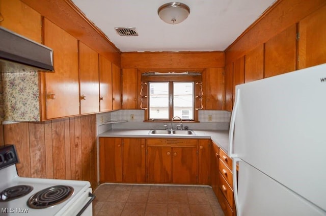 kitchen featuring light countertops, visible vents, brown cabinetry, a sink, and white appliances