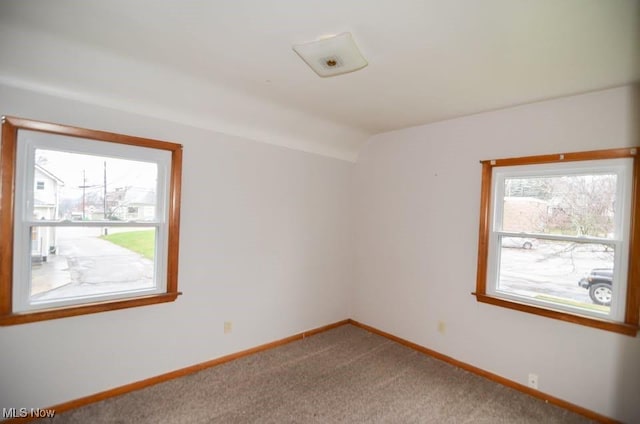 empty room featuring lofted ceiling, carpet flooring, and baseboards