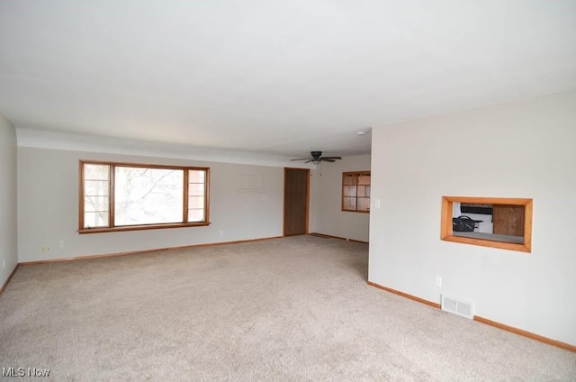 unfurnished room featuring baseboards, visible vents, a ceiling fan, and light colored carpet