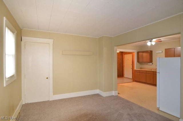 empty room with baseboards, a sink, a wealth of natural light, and light colored carpet