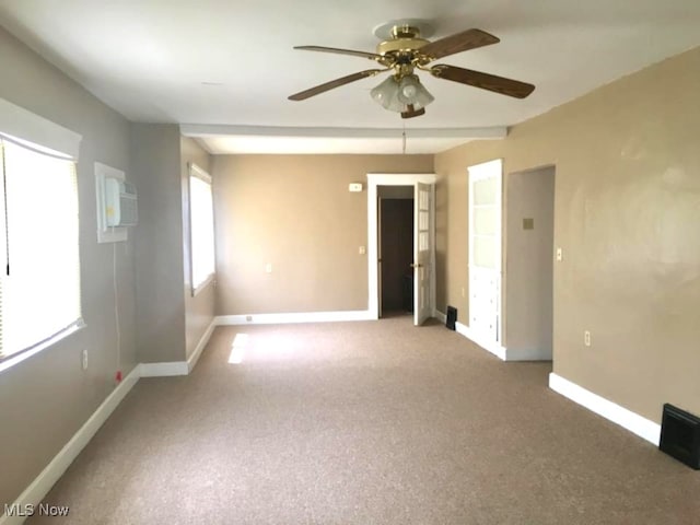 carpeted spare room with an AC wall unit, ceiling fan, and baseboards