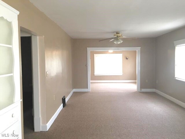 spare room featuring ceiling fan, carpet, and baseboards