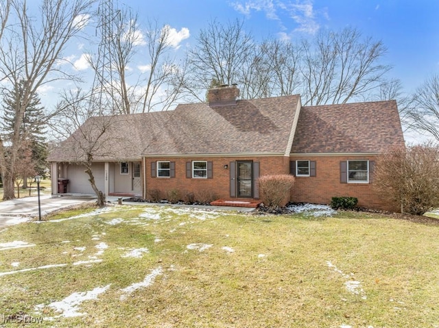 view of front facade with brick siding, a chimney, a shingled roof, a front yard, and driveway