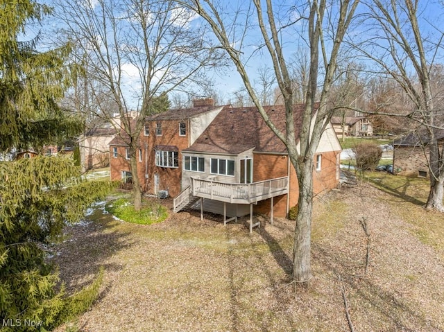 back of house with a deck, dirt driveway, and stairs