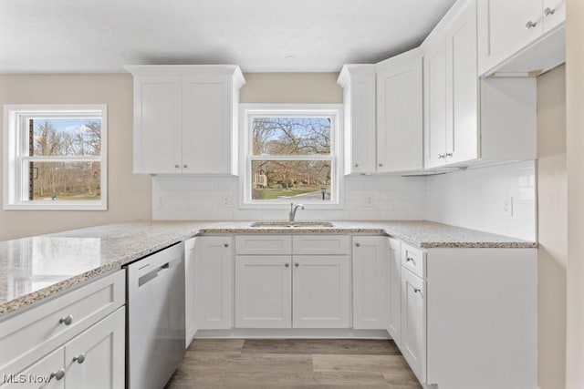 kitchen featuring light stone counters, light wood-style flooring, a sink, white cabinets, and stainless steel dishwasher