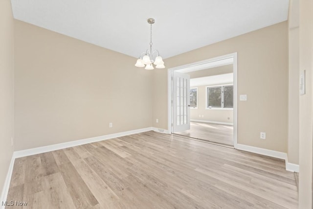 empty room featuring light wood finished floors, baseboards, and an inviting chandelier