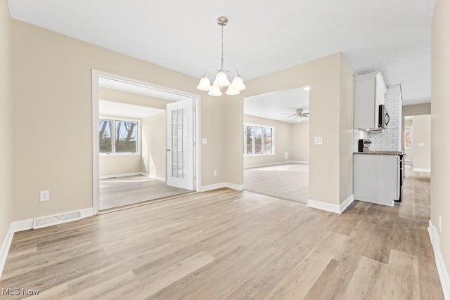 unfurnished dining area with light wood-style flooring, plenty of natural light, visible vents, and baseboards