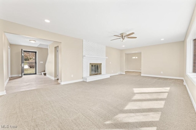 unfurnished living room with baseboards, a fireplace, and light colored carpet