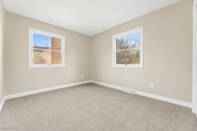 carpeted empty room with plenty of natural light, visible vents, and baseboards