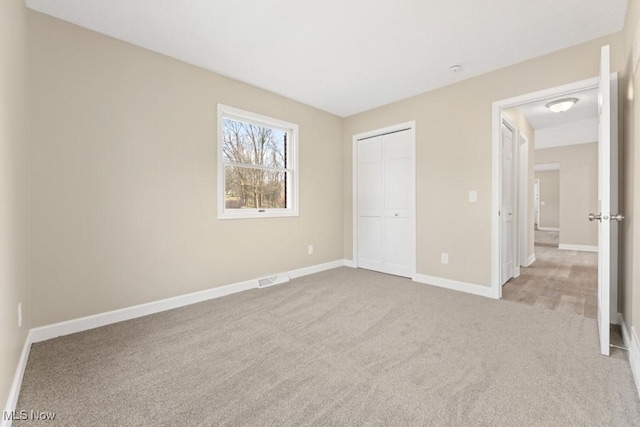 unfurnished bedroom featuring carpet floors, a closet, visible vents, and baseboards