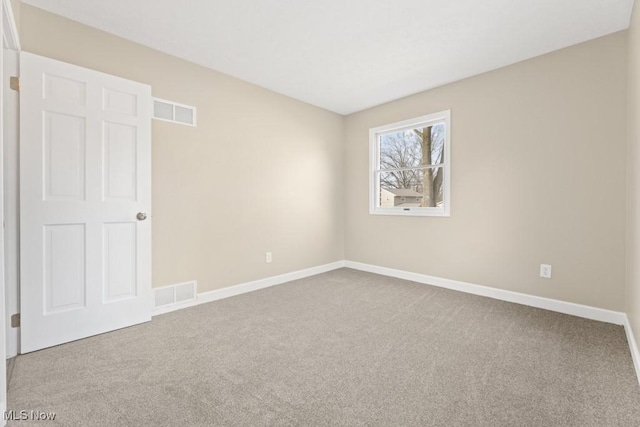 unfurnished room featuring carpet floors, visible vents, and baseboards