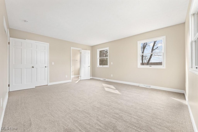 unfurnished bedroom with light carpet, visible vents, and baseboards