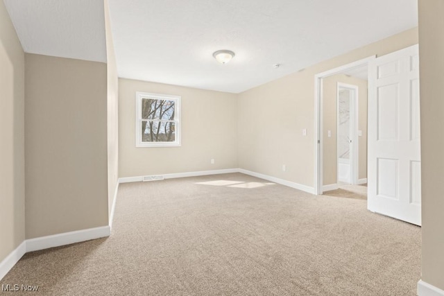 carpeted empty room with visible vents and baseboards