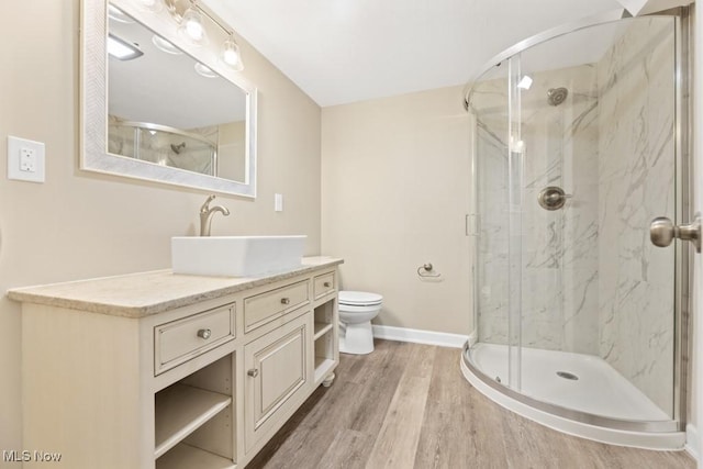 bathroom with vanity, a marble finish shower, and wood finished floors