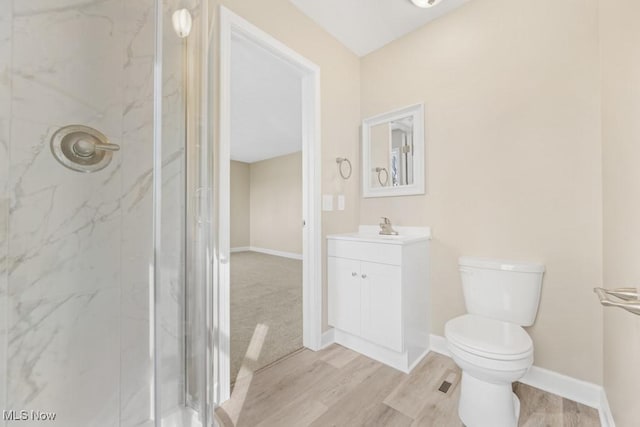 bathroom with a marble finish shower, toilet, vanity, wood finished floors, and baseboards