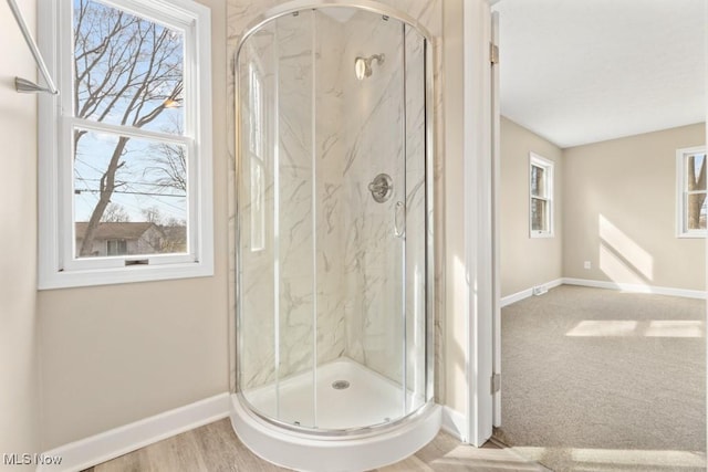 full bathroom featuring baseboards, a marble finish shower, and a healthy amount of sunlight