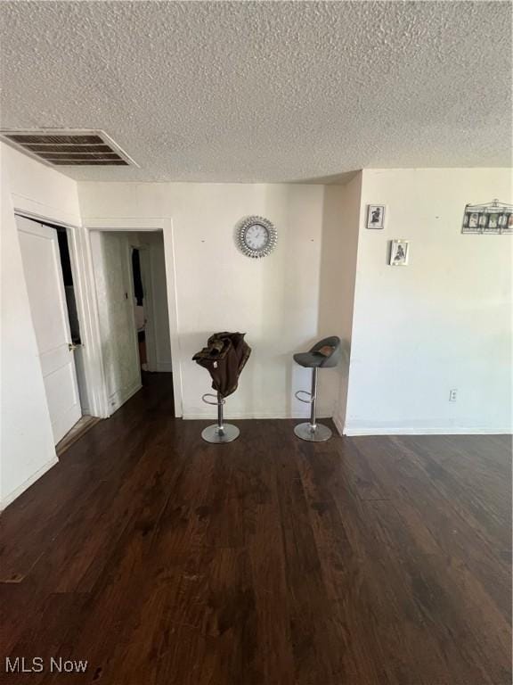 hall with visible vents, a textured ceiling, and wood finished floors