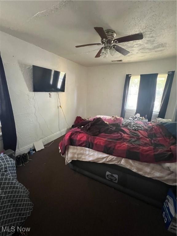 bedroom with ceiling fan, a textured ceiling, and baseboards