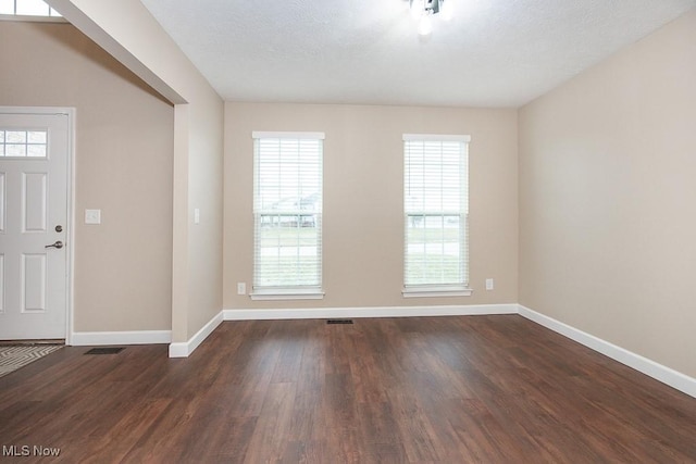 entrance foyer with visible vents, a textured ceiling, dark wood-type flooring, and baseboards