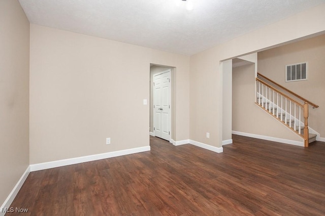 unfurnished room with visible vents, baseboards, wood finished floors, and stairs