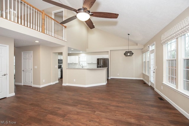 unfurnished living room featuring a sink, visible vents, baseboards, and dark wood-style floors