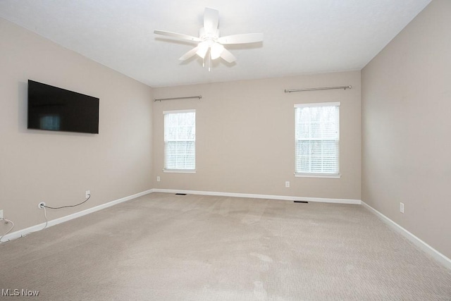 spare room with a wealth of natural light, baseboards, and light colored carpet