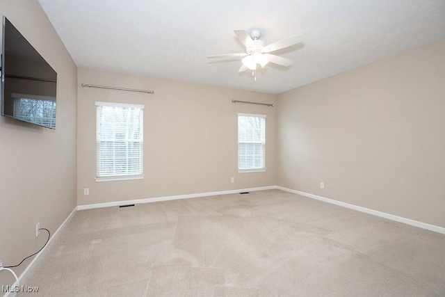 carpeted empty room with visible vents, ceiling fan, and baseboards