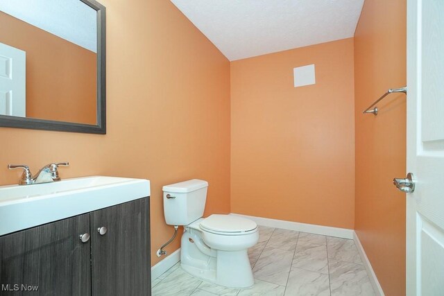 bathroom featuring vanity, toilet, baseboards, and marble finish floor