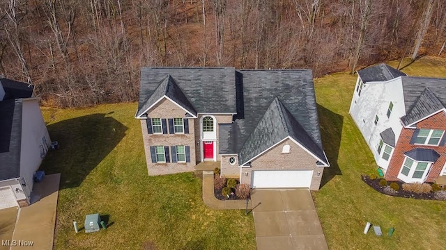 view of front of house with brick siding, driveway, an attached garage, and a front lawn