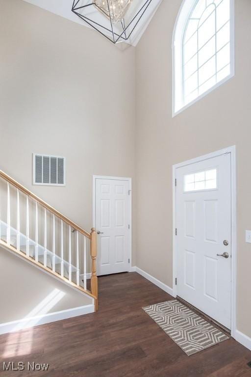 entryway featuring stairway, wood finished floors, visible vents, baseboards, and a towering ceiling