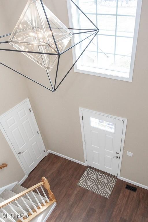 foyer entrance featuring visible vents, stairway, baseboards, and wood finished floors