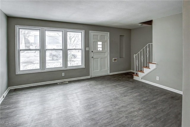 foyer entrance featuring stairs, dark wood-style flooring, visible vents, and baseboards