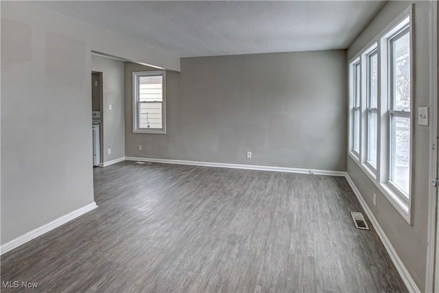 empty room featuring baseboards, visible vents, and dark wood-type flooring