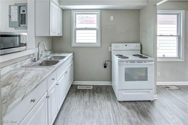 kitchen with white electric range, stainless steel microwave, visible vents, and a sink