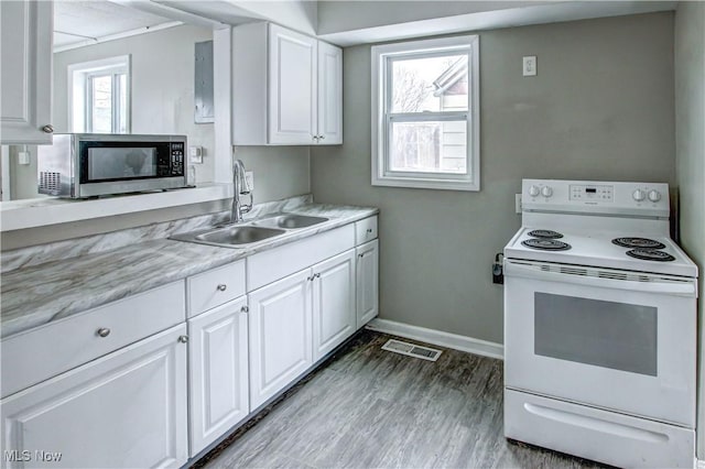 kitchen featuring white range with electric stovetop, light countertops, stainless steel microwave, visible vents, and a sink